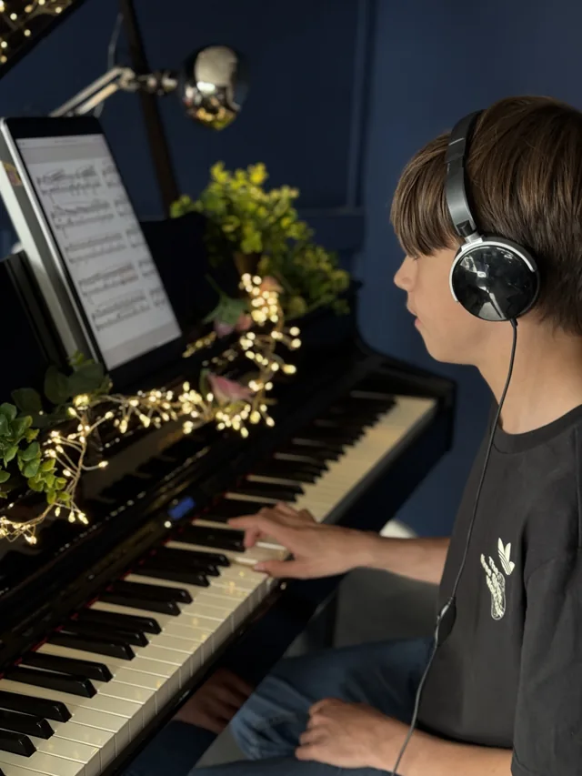 A pupil playing piano with headphones at The Piano Lab in Liverpool